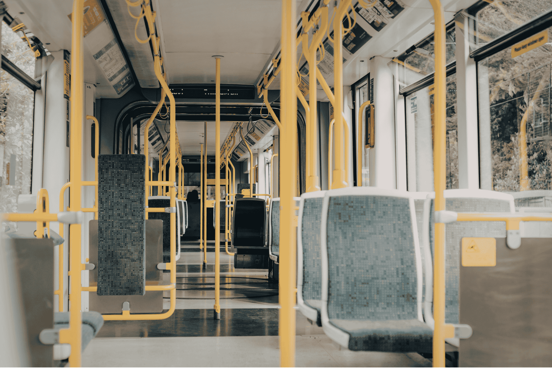 Interior view of an empty Cincinnati public transit vehicle featuring yellow handrails, gray seating, and large windows.