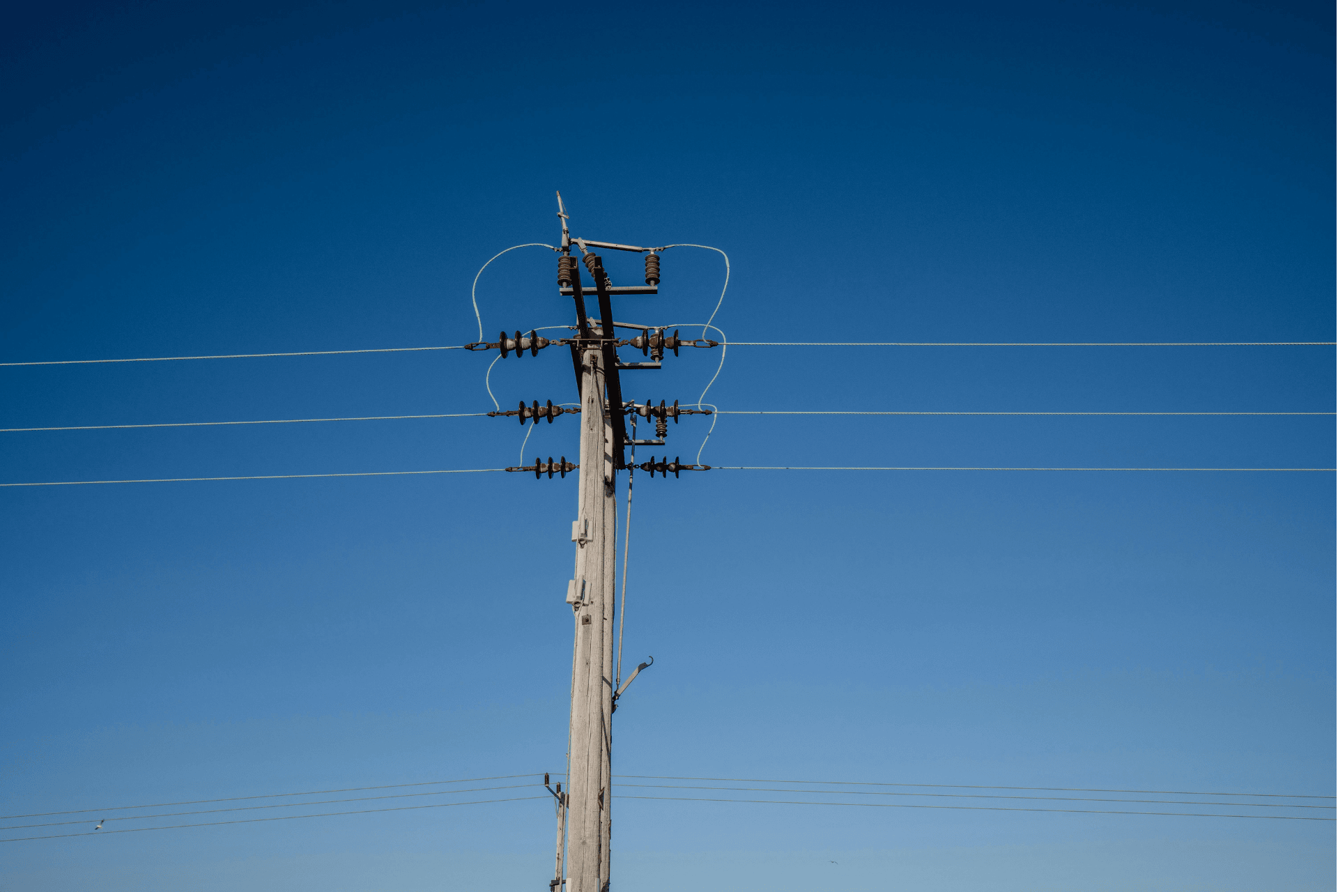 A wooden utility pole with power lines and a transformer against a clear blue sky, illustrating Cincinnati utility infrastructure.