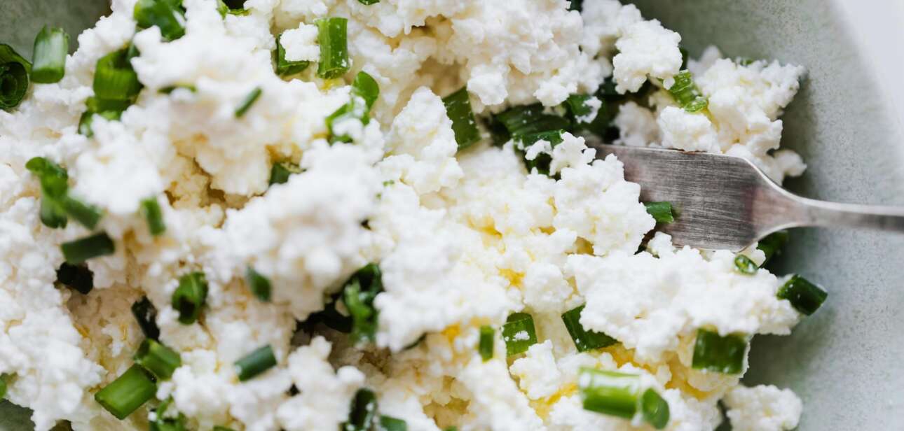 A close-up of a bowl of cottage cheese garnished with green chives, illustrating the recent dairy product recall in Cincinnati.