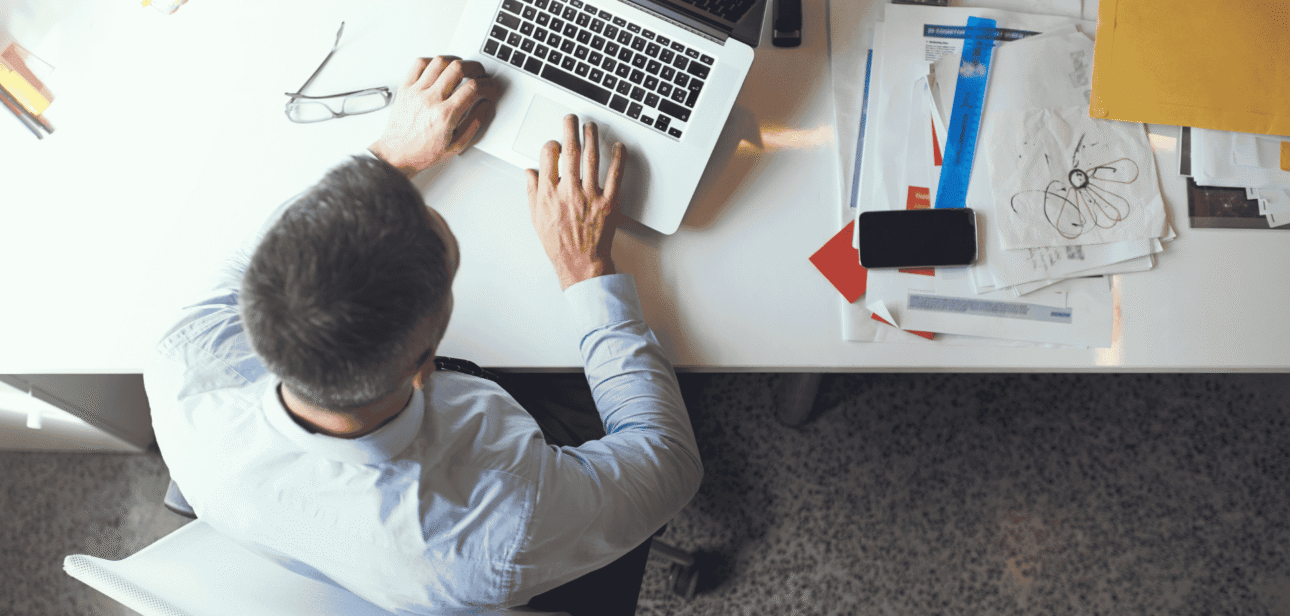 Overhead view of a professional working at a desk with a laptop and papers, illustrating downtown Cincinnati office vacancy trends.
