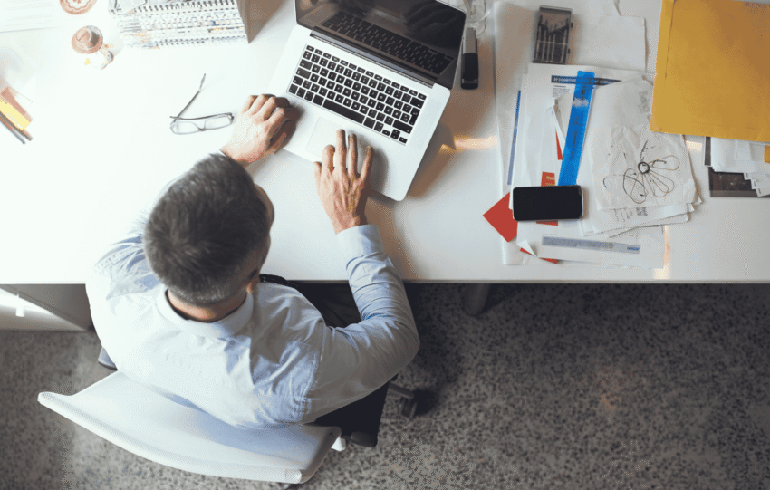 Overhead view of a professional working at a desk with a laptop and papers, illustrating downtown Cincinnati office vacancy trends.