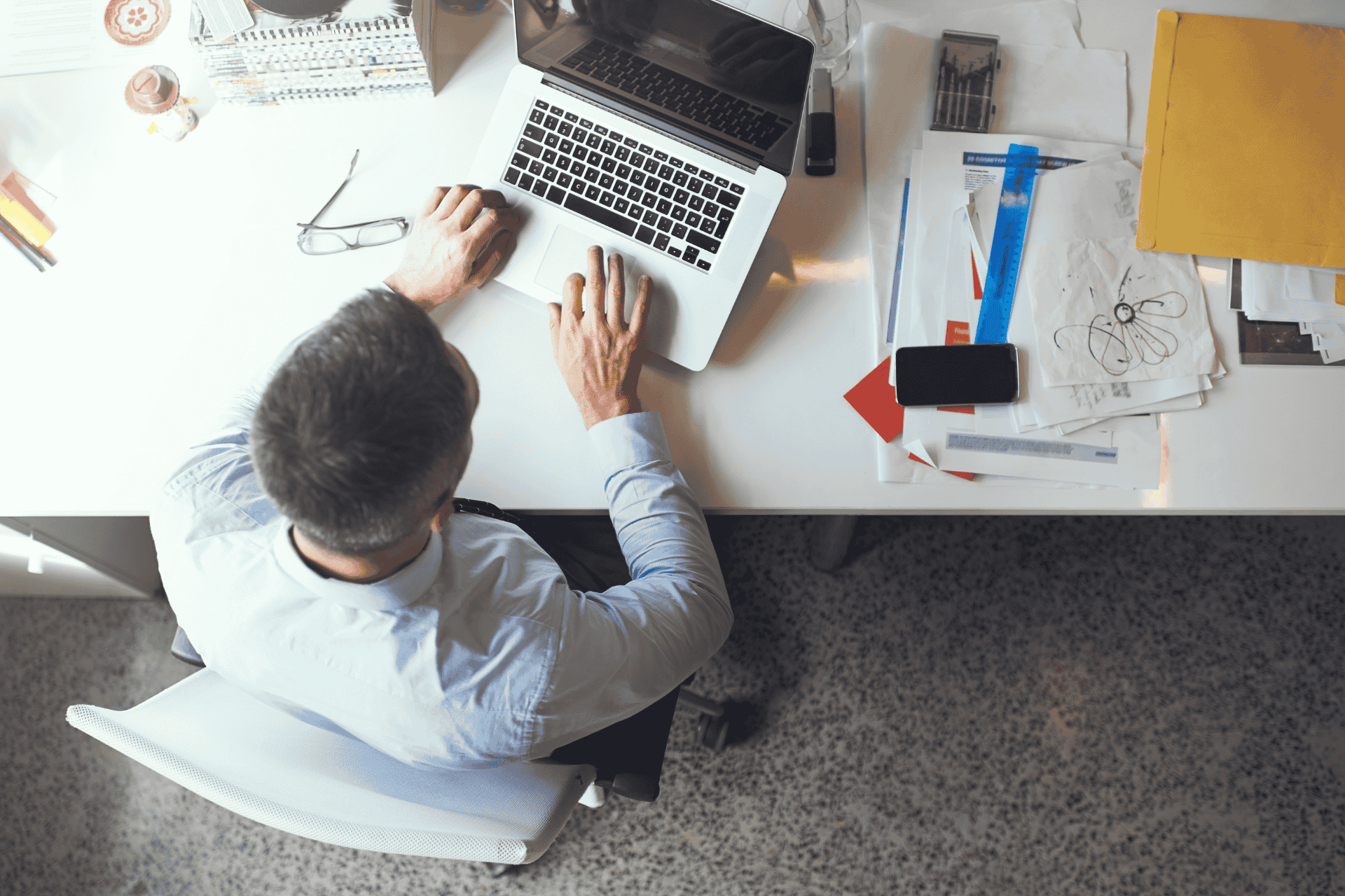 Overhead view of a professional working at a desk with a laptop and papers, illustrating downtown Cincinnati office vacancy trends.