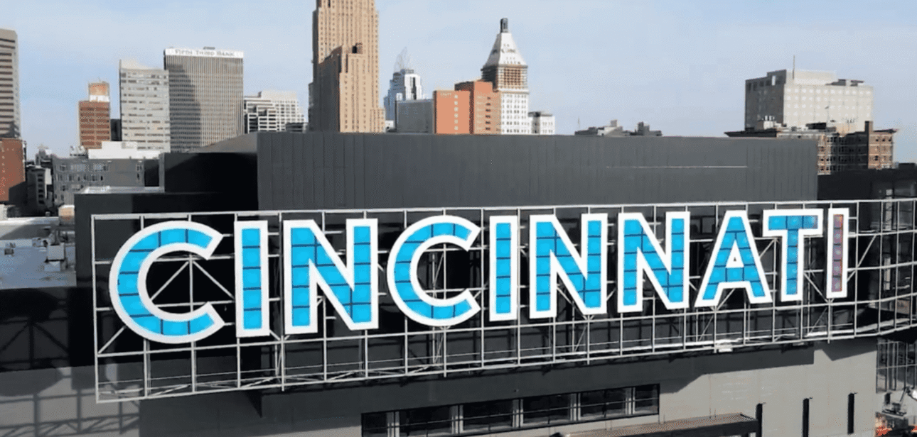 The large CINCINNATI sign on the side of the Duke Energy Convention Center with the First Financial Center skyscraper rising in the background.