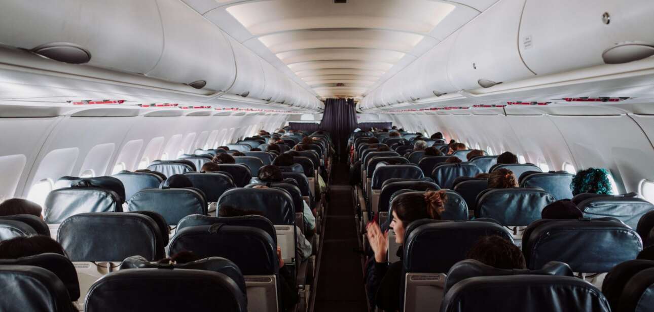 Passengers sitting in a dimly lit airplane cabin waiting during a flight disruption at CVG airport.