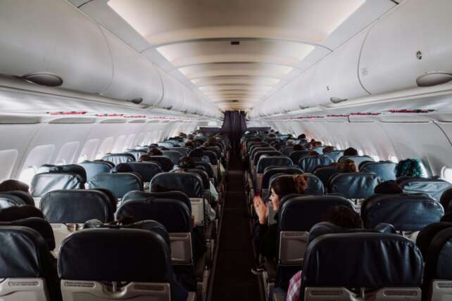 Passengers sitting in a dimly lit airplane cabin waiting during a flight disruption at CVG airport.