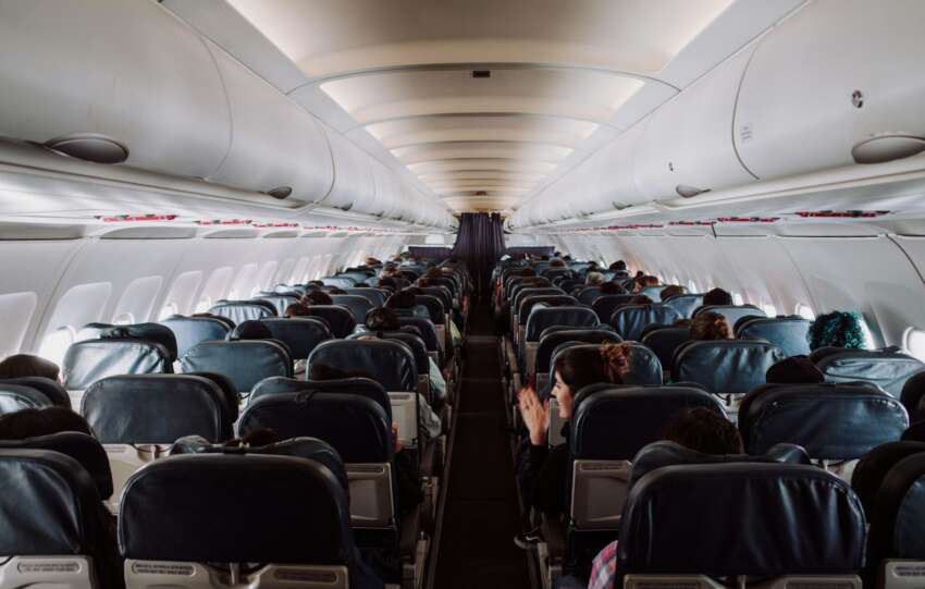 Passengers sitting in a dimly lit airplane cabin waiting during a flight disruption at CVG airport.