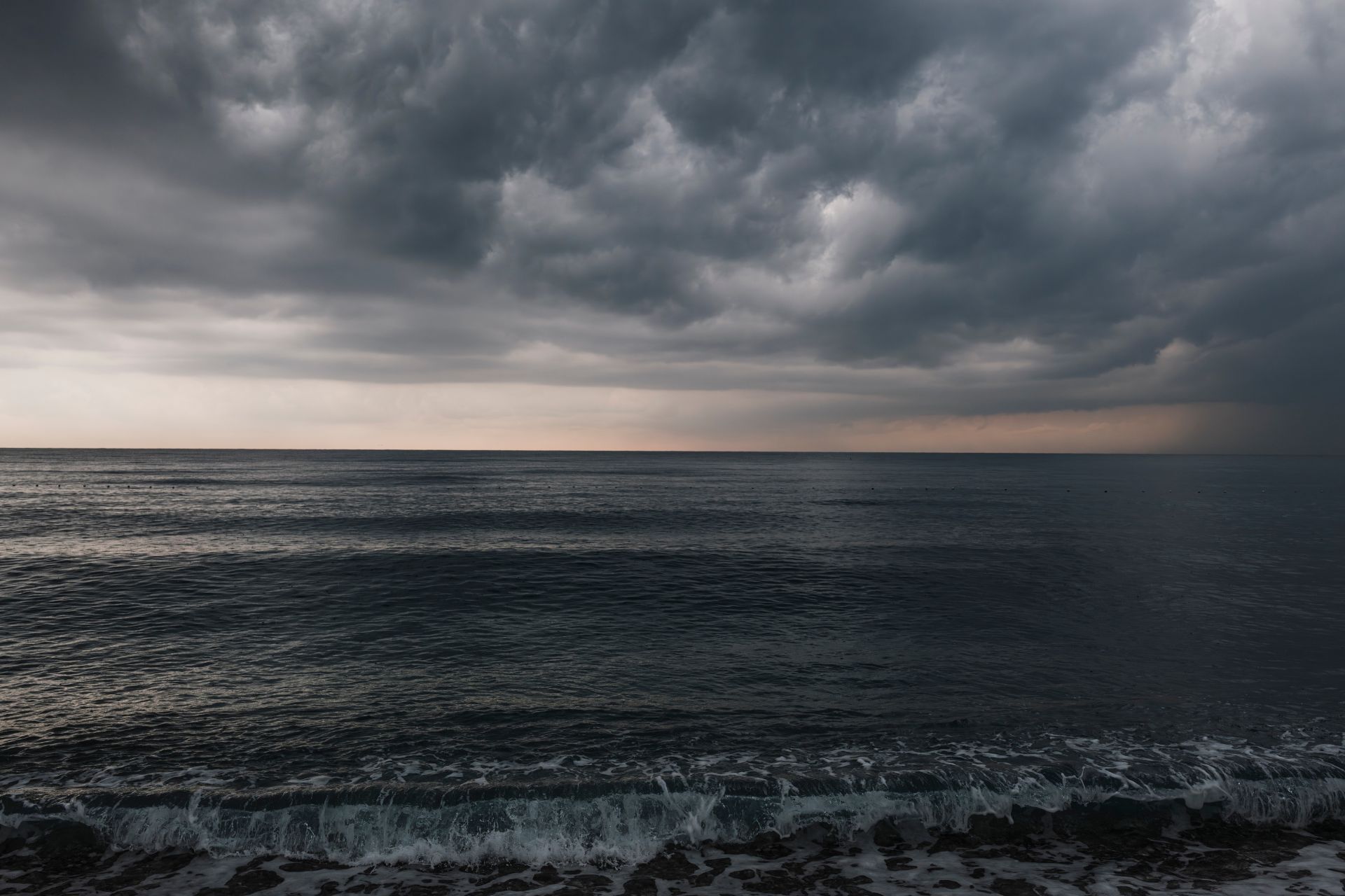 Dark, heavy storm clouds rolling in over a turbulent body of water.