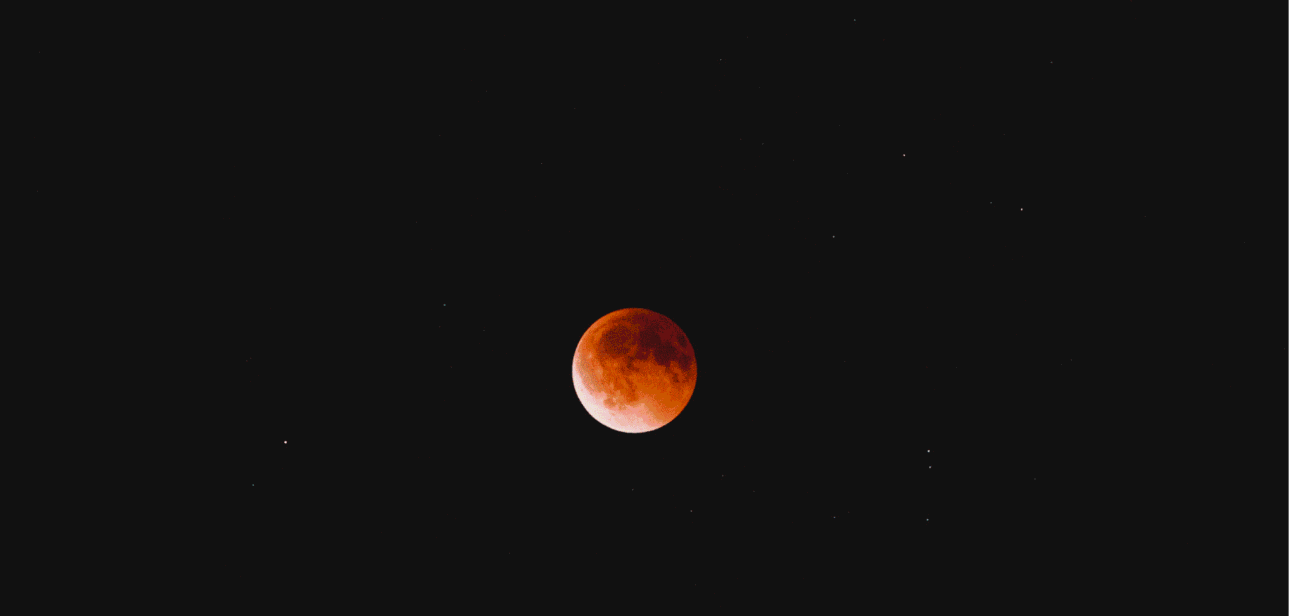 A total lunar eclipse, also known as a blood moon, glowing deep red against a dark night sky.
