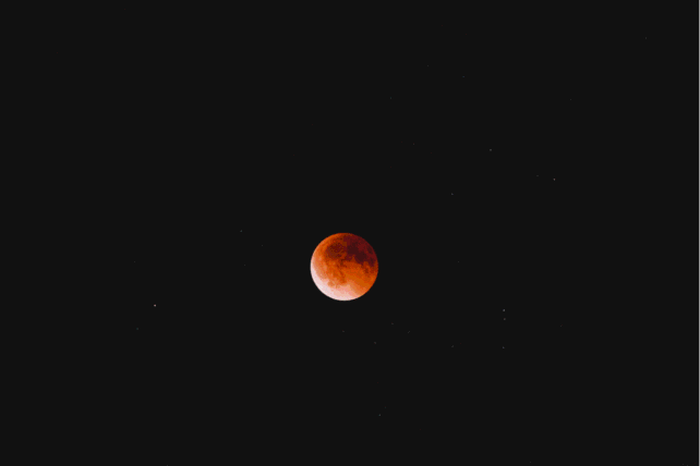 A total lunar eclipse, also known as a blood moon, glowing deep red against a dark night sky.