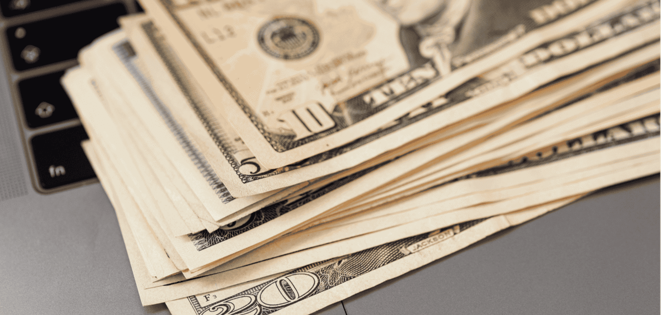 A stack of US fifty-dollar bills lying on a dark surface, illustrating financial crime or theft.