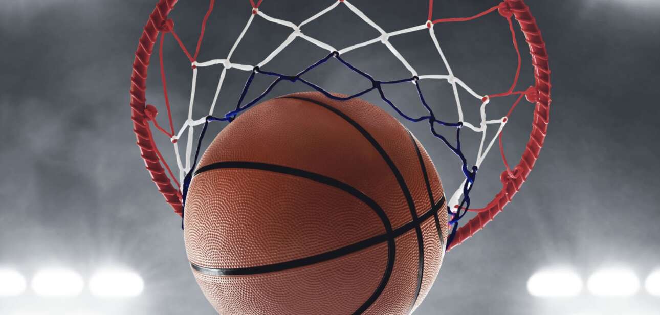 A basketball swishing through a net under bright stadium lights, symbolizing intense Cincinnati college basketball matchups like the Crosstown Shootout.