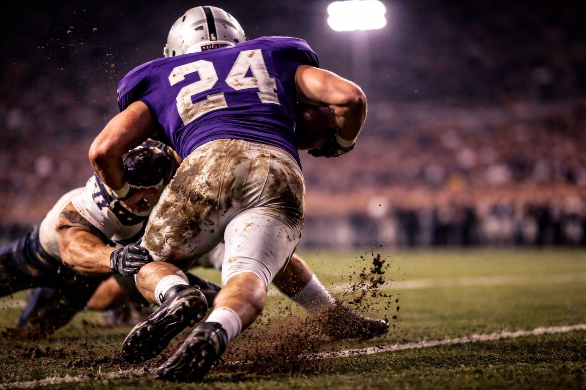A Cincinnati high school football player wearing a purple and white jersey with number 24 breaks a tackle during a night game.