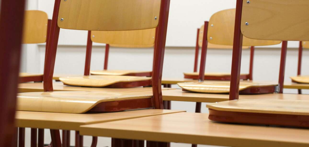 Rows of empty wooden student desks in a classroom.