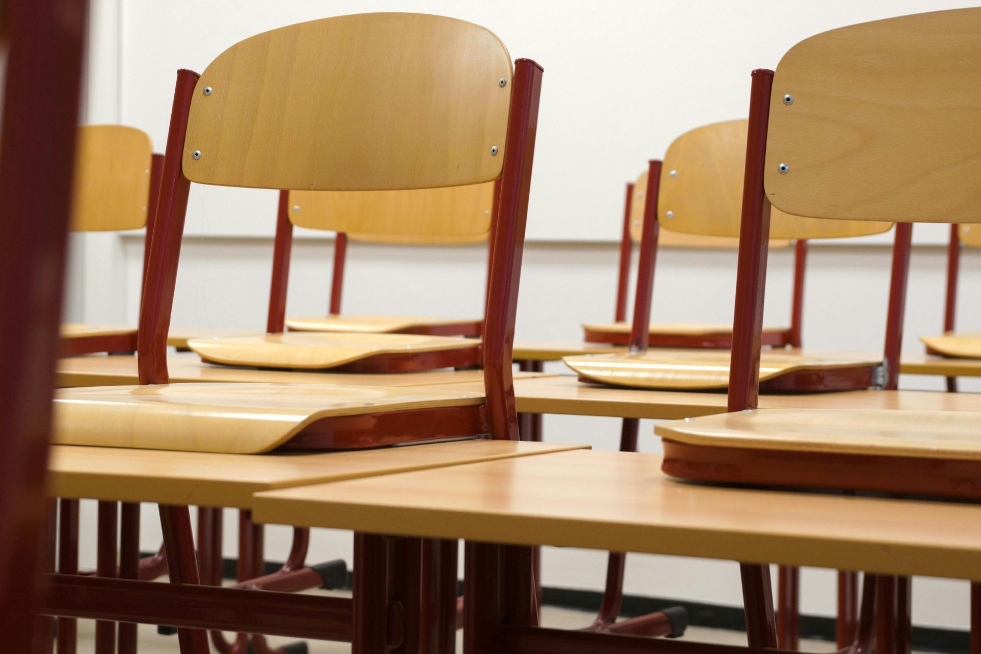 Rows of empty wooden student desks in a classroom.