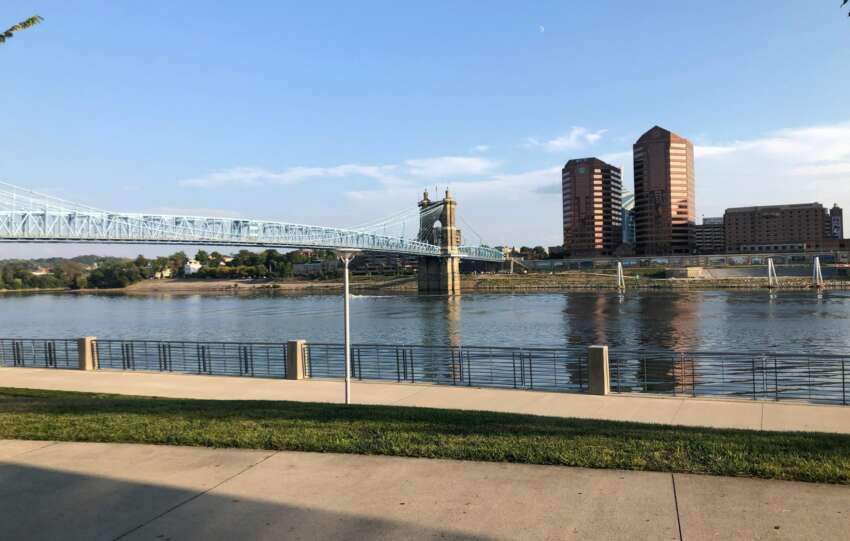 View of the John A. Roebling Suspension Bridge over the Ohio River with a news headline overlay regarding Cincinnati resident satisfaction.