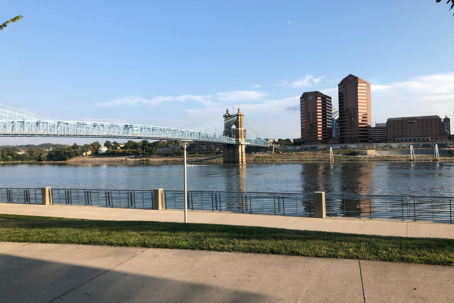 View of the John A. Roebling Suspension Bridge over the Ohio River with a news headline overlay regarding Cincinnati resident satisfaction.