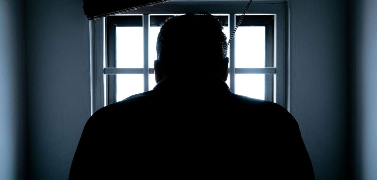 Silhouette of a person standing before a window in a dark room, illustrating a report on the Riverfront Live shooting investigation in Cincinnati.
