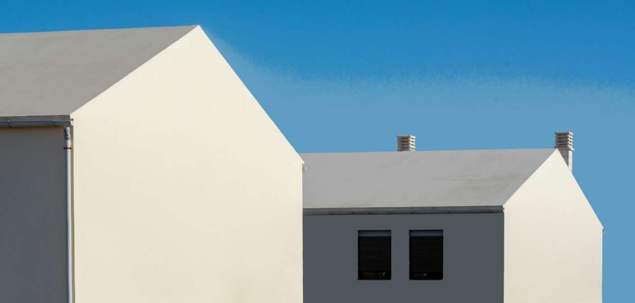 Modern white and gray residential houses in Ohio against a clear blue sky, highlighting the ongoing Ohio housing crisis.