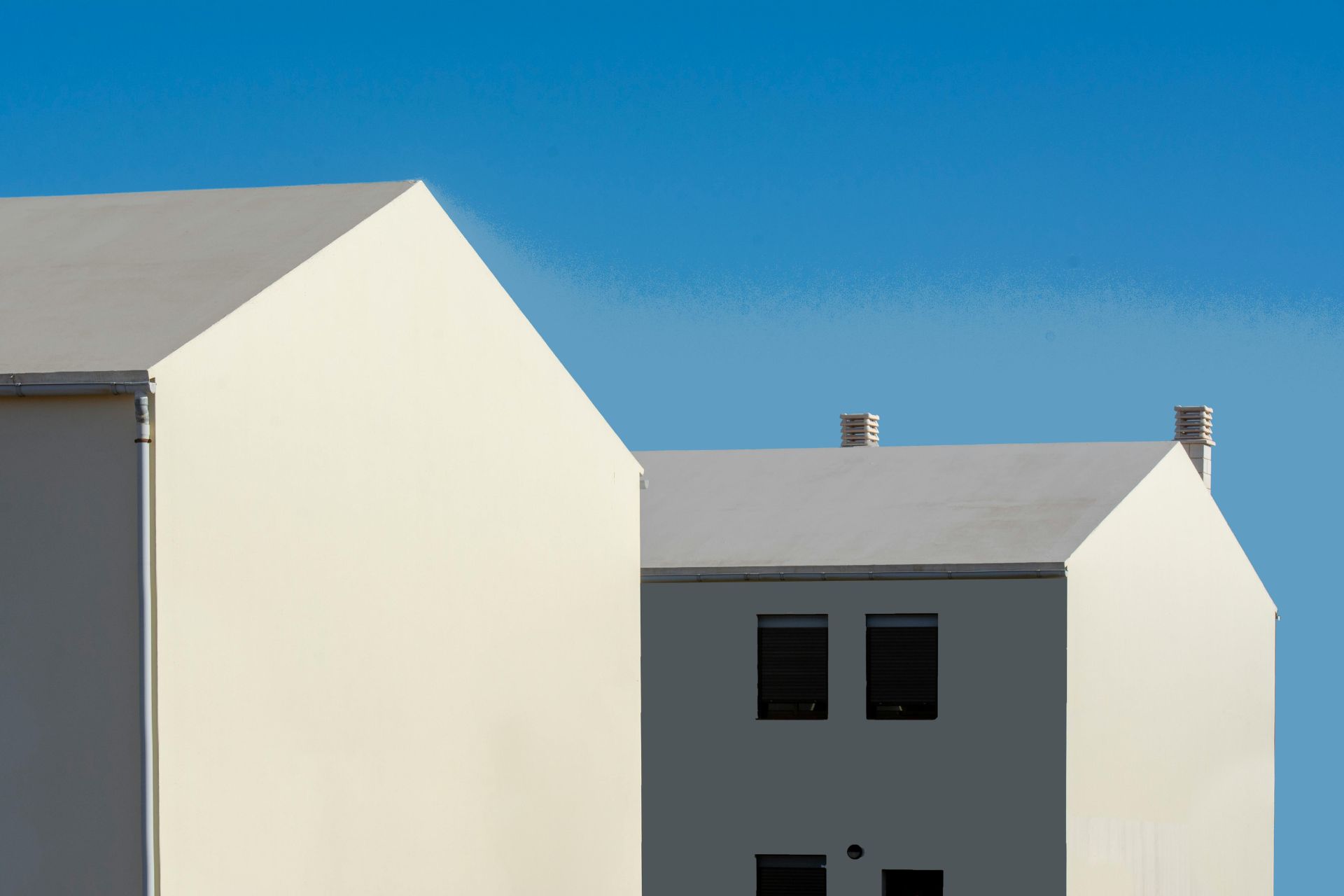 Modern white and gray residential houses in Ohio against a clear blue sky, highlighting the ongoing Ohio housing crisis.