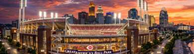 A wide-angle, cinematic view of the Great American Ball Park exterior in Cincinnati at sunset with the city skyline in the background.