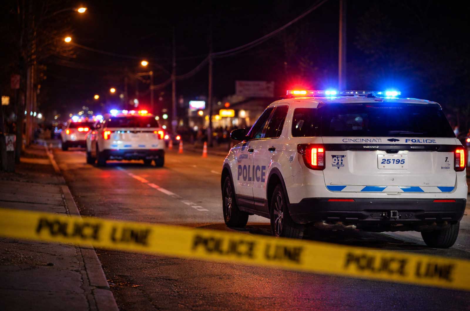 Cincinnati police vehicles block a street at night with emergency lights active following the Riverfront Live shooting in the East End