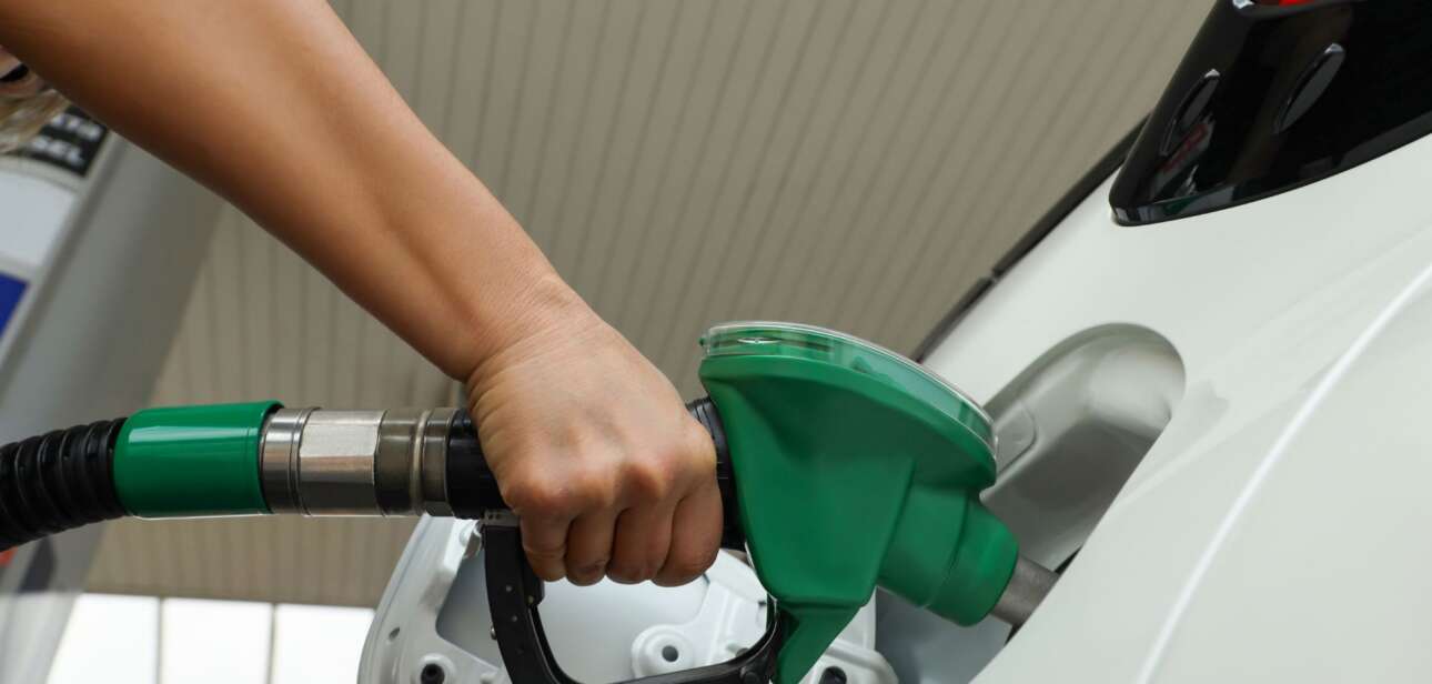 A driver pumps gas into a white vehicle, illustrating the recent fuel price surge affecting Springfield, Dayton, and Cincinnati.