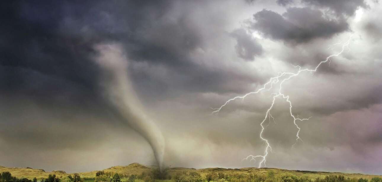 A dark funnel cloud touches down in a rural green field under ominous storm clouds with visible lightning strikes.