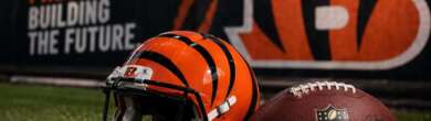 Cincinnati Bengals helmet and NFL football on turf with "Building Pressure, Building the Future" branding in the background.