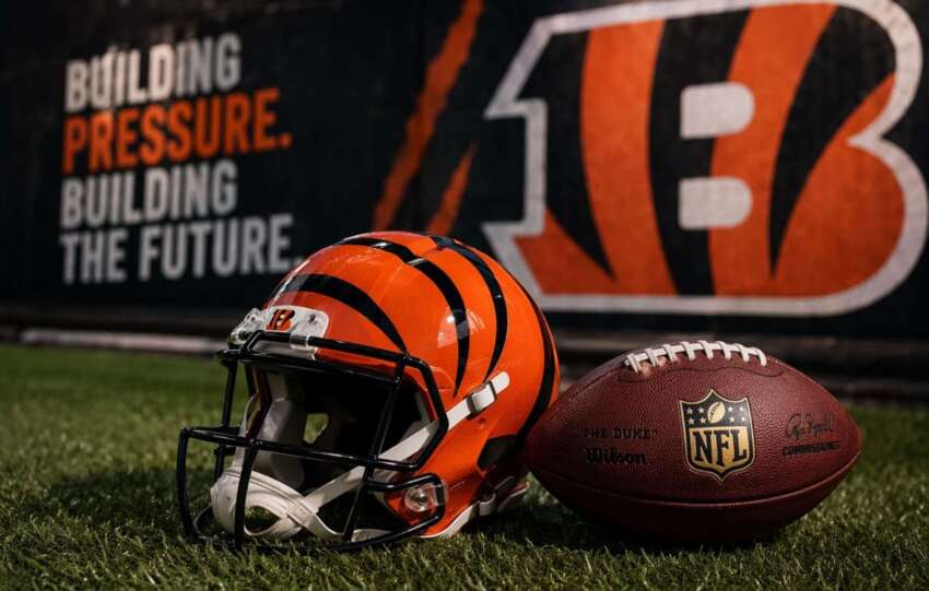 Cincinnati Bengals helmet and NFL football on turf with "Building Pressure, Building the Future" branding in the background.