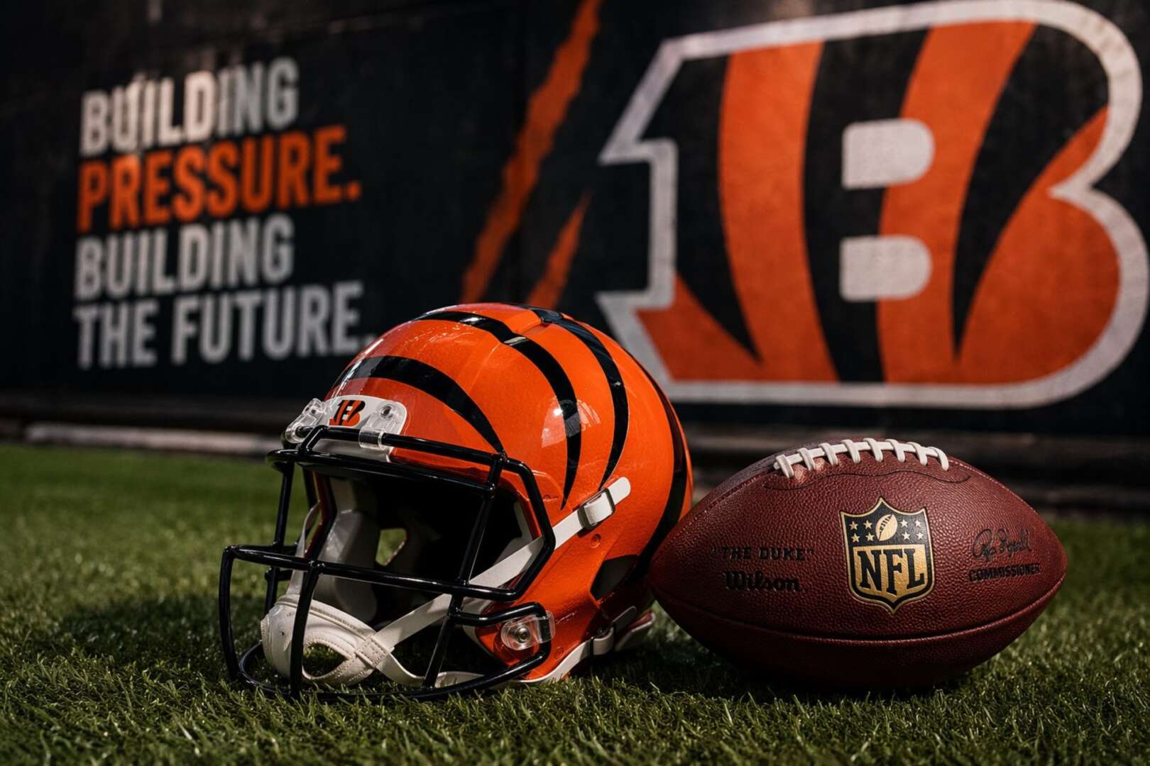 Cincinnati Bengals helmet and NFL football on turf with "Building Pressure, Building the Future" branding in the background.