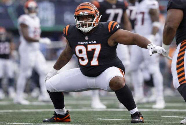 Cincinnati Bengals defensive lineman in orange uniform crouched at the line of scrimmage during an NFL game