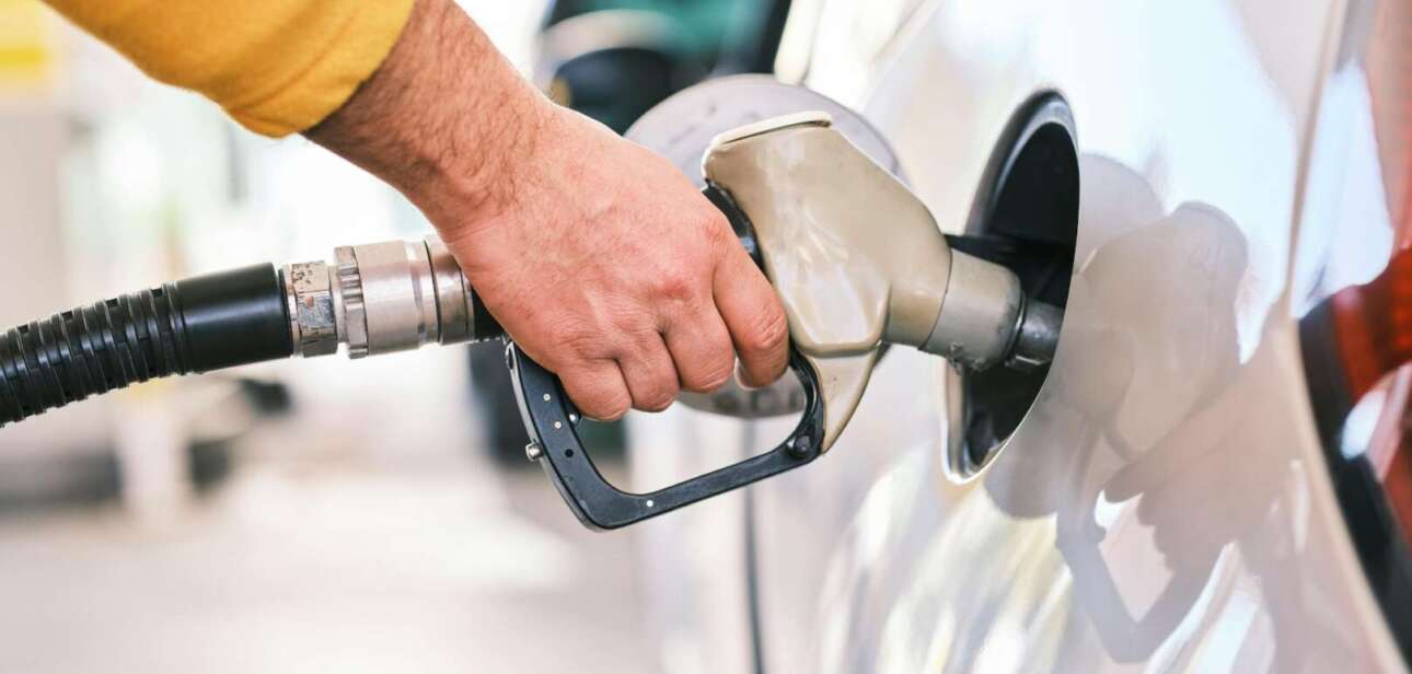 Close-up of a person pumping gasoline into a car at a gas station in Cincinnati, Ohio, during a 2026 fuel price surge.