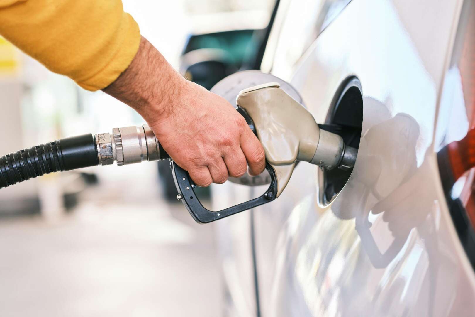 Close-up of a person pumping gasoline into a car at a gas station in Cincinnati, Ohio, during a 2026 fuel price surge.