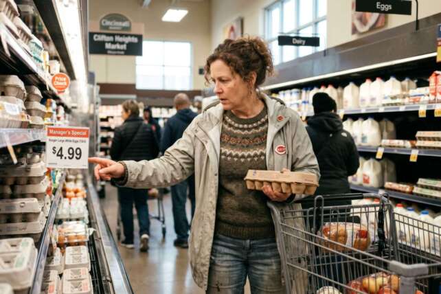 A woman checking a product in a supermarket aisle, highlighting Cincinnati grocery prices in 2026.