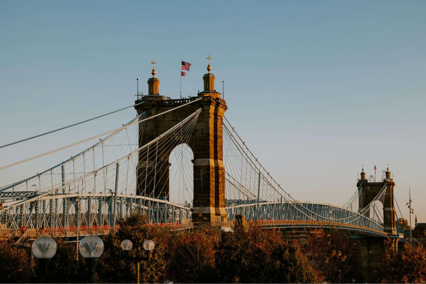 John A. Roebling Suspension Bridge in Cincinnati at sunset, symbolizing infrastructure and railway spending shifts in Ohio.