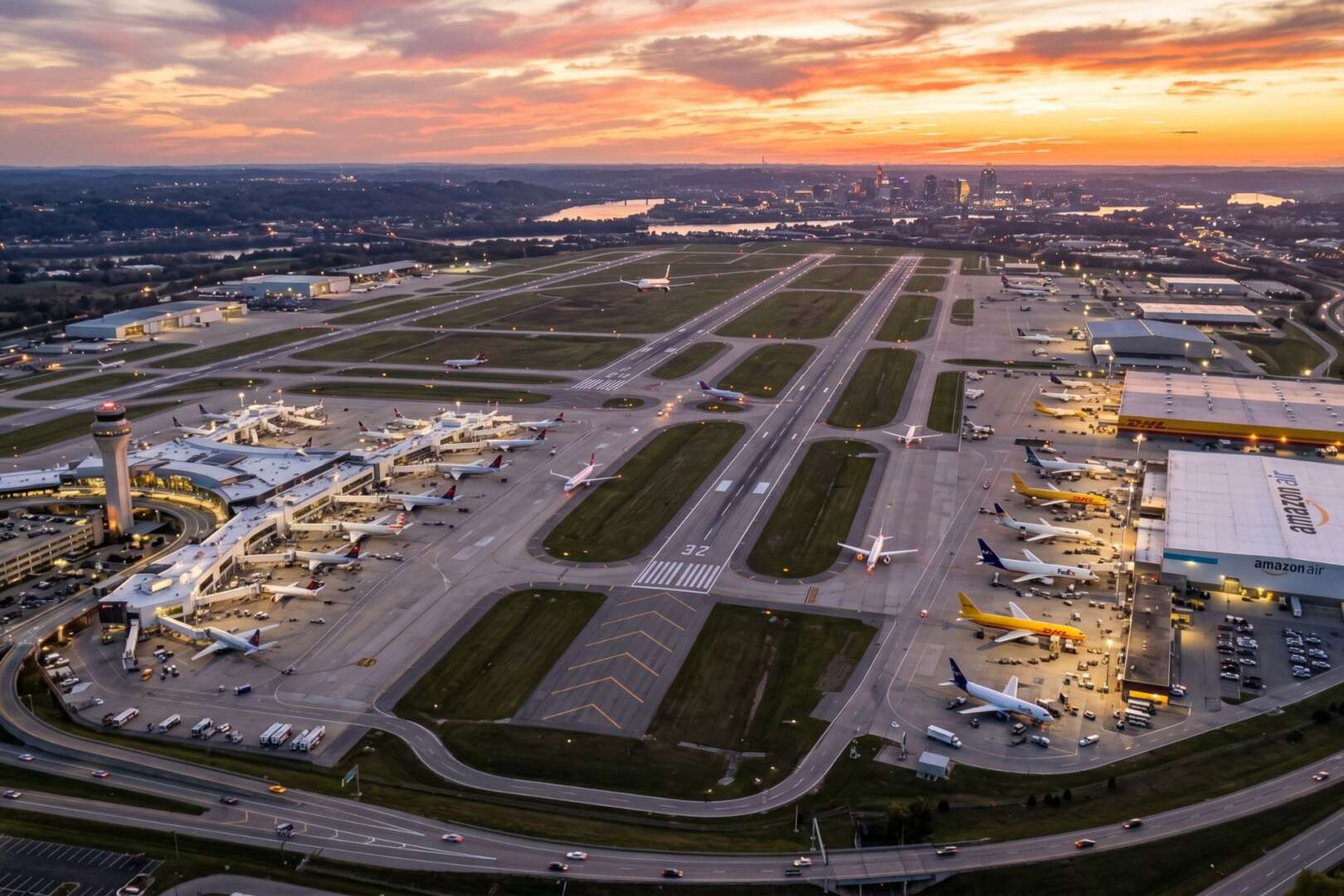 Aerial view of the Cincinnati/Northern Kentucky International Airport (CVG) at sunset, showcasing the expansive runway and terminal infrastructure.