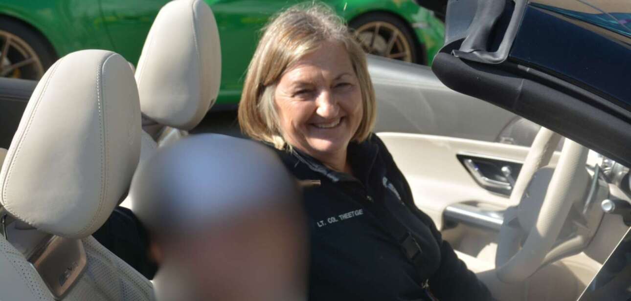 Cincinnati Police Chief Teresa Theetge smiling in the passenger seat of a car during an event.