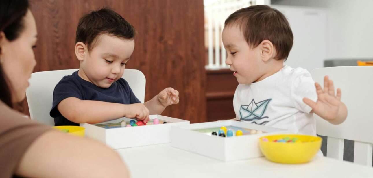 Two young children playing with colorful educational toys at a table in a childcare center.