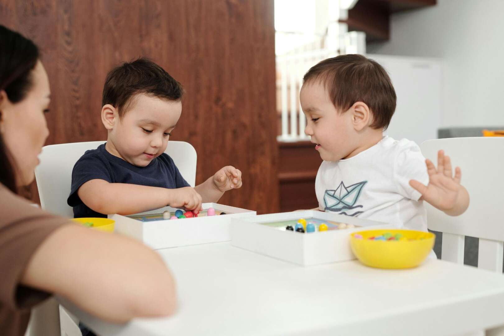Two young children playing with colorful educational toys at a table in a childcare center.