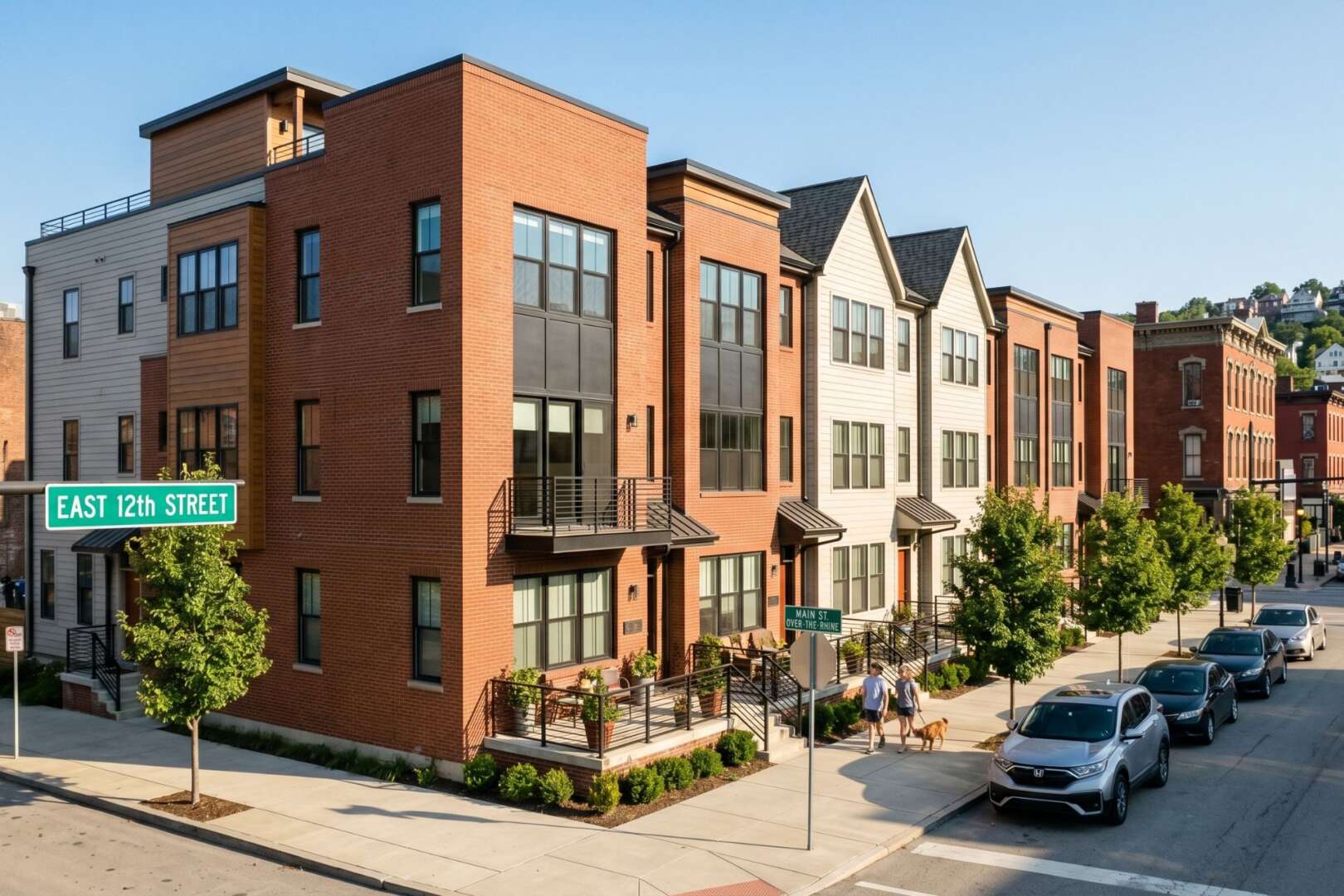 A bright, high-quality street-level photograph of newly built or renovated rowhouses, duplexes, or townhomes in a recognizable Cincinnati neighborhood.