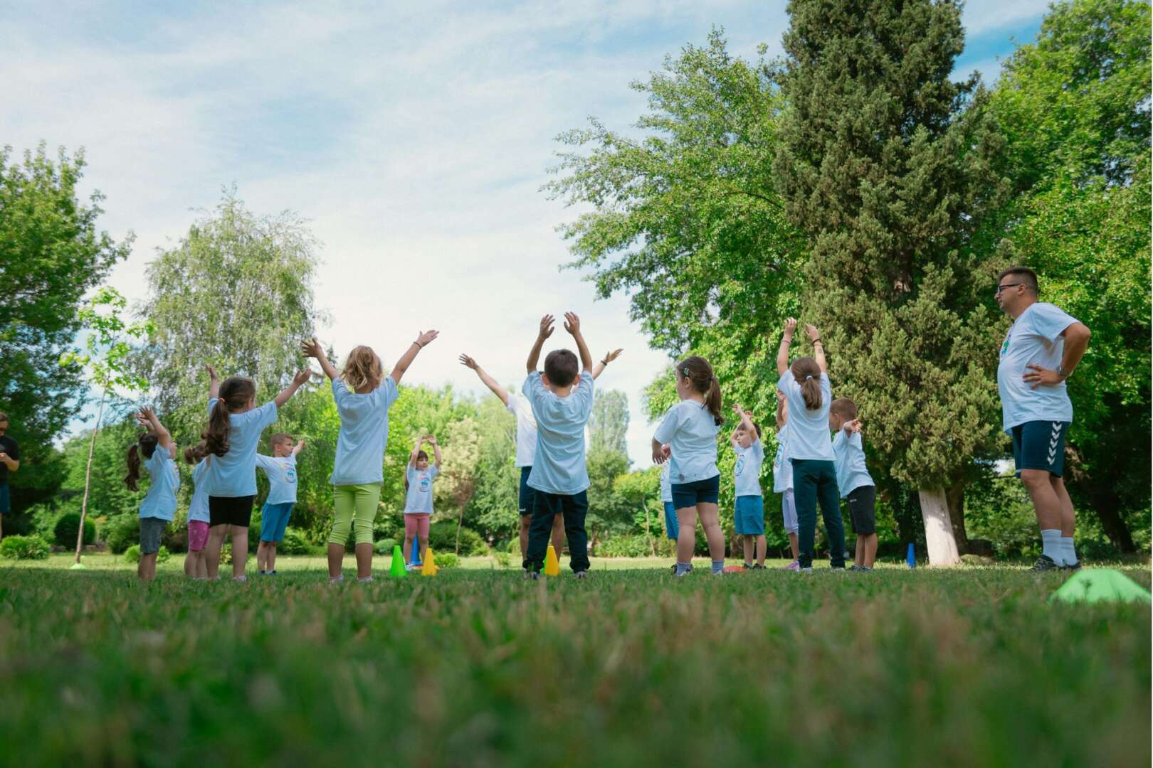 A group of children and an instructor participating in outdoor activities and exercises at a Cincinnati summer camp.