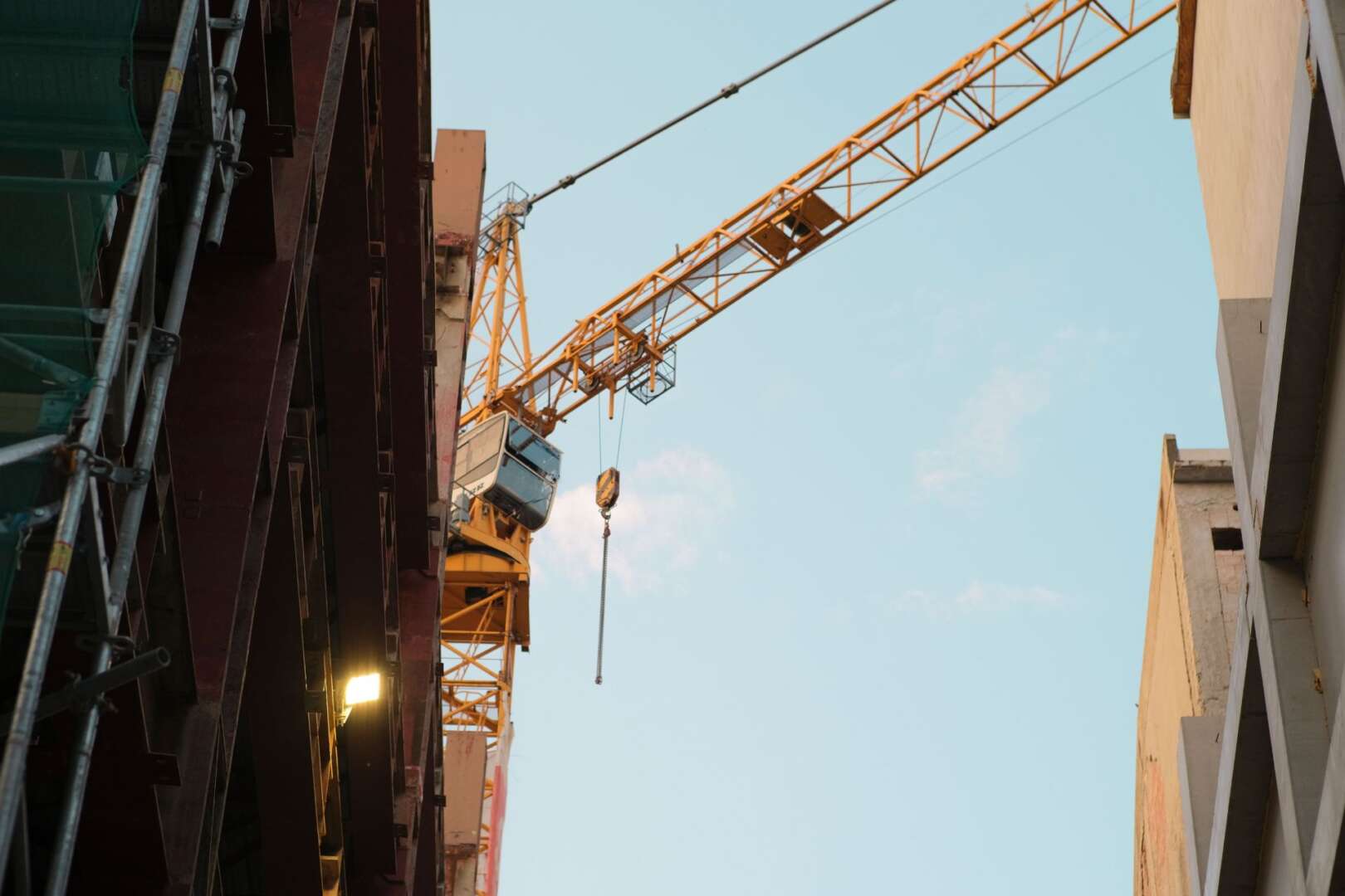 A yellow construction crane operating at an urban building site, representing the impact of 2026 construction costs in Cincinnati.