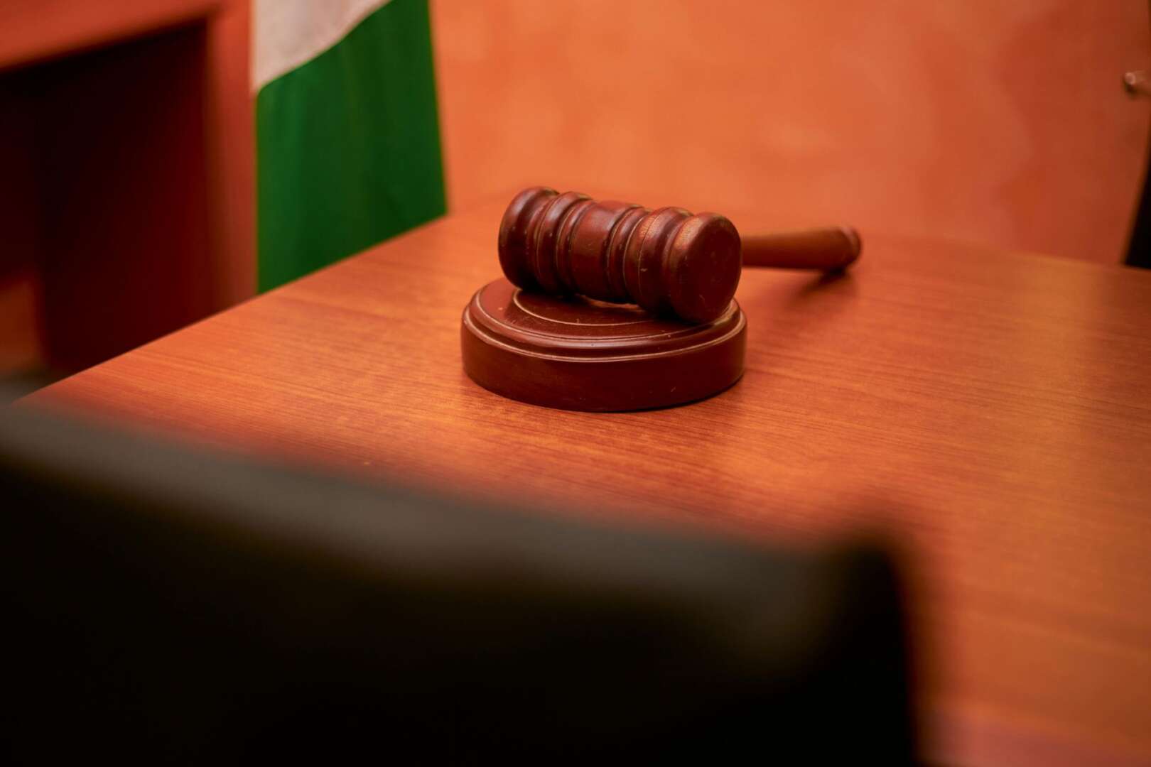 A wooden judicial gavel resting on a wooden desk.