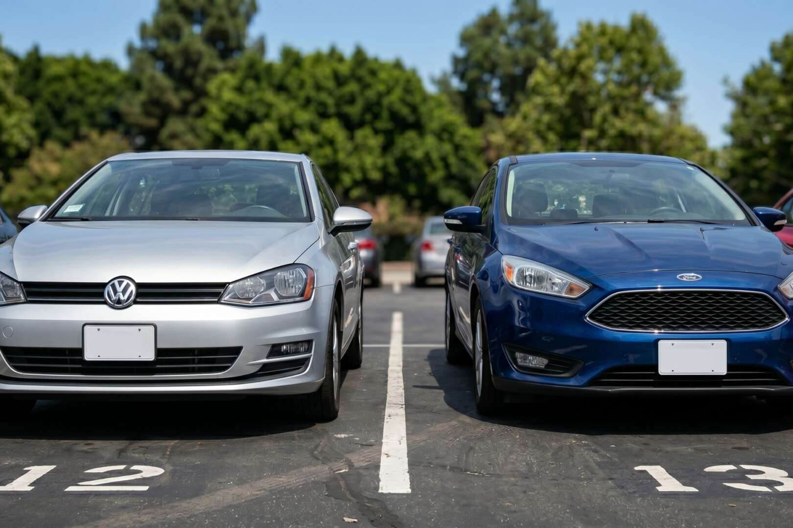 A silver Volkswagen and a blue Ford parked in numbered stalls at an outdoor Cincinnati parking lot.