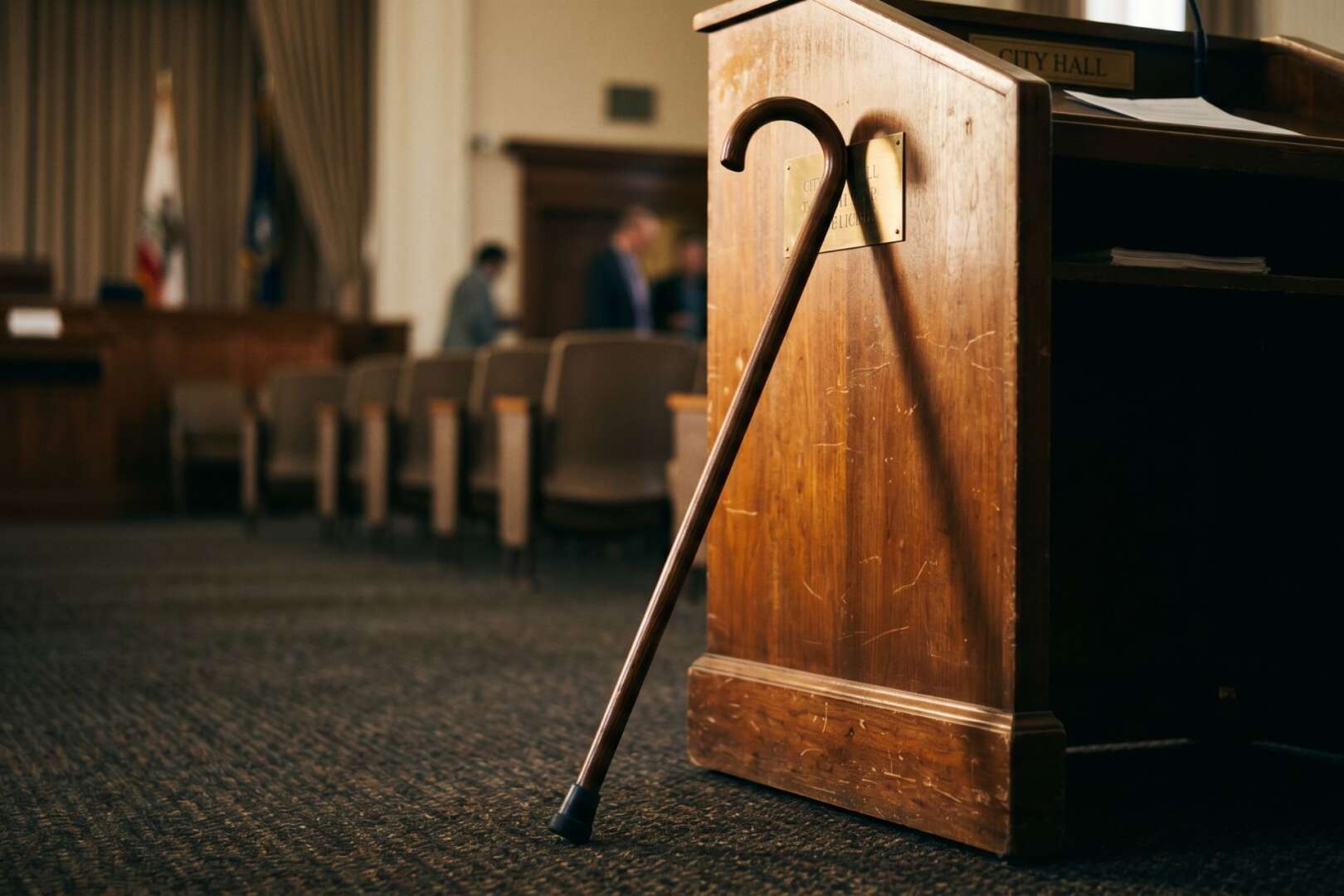 A wooden sword cane leans against a podium.