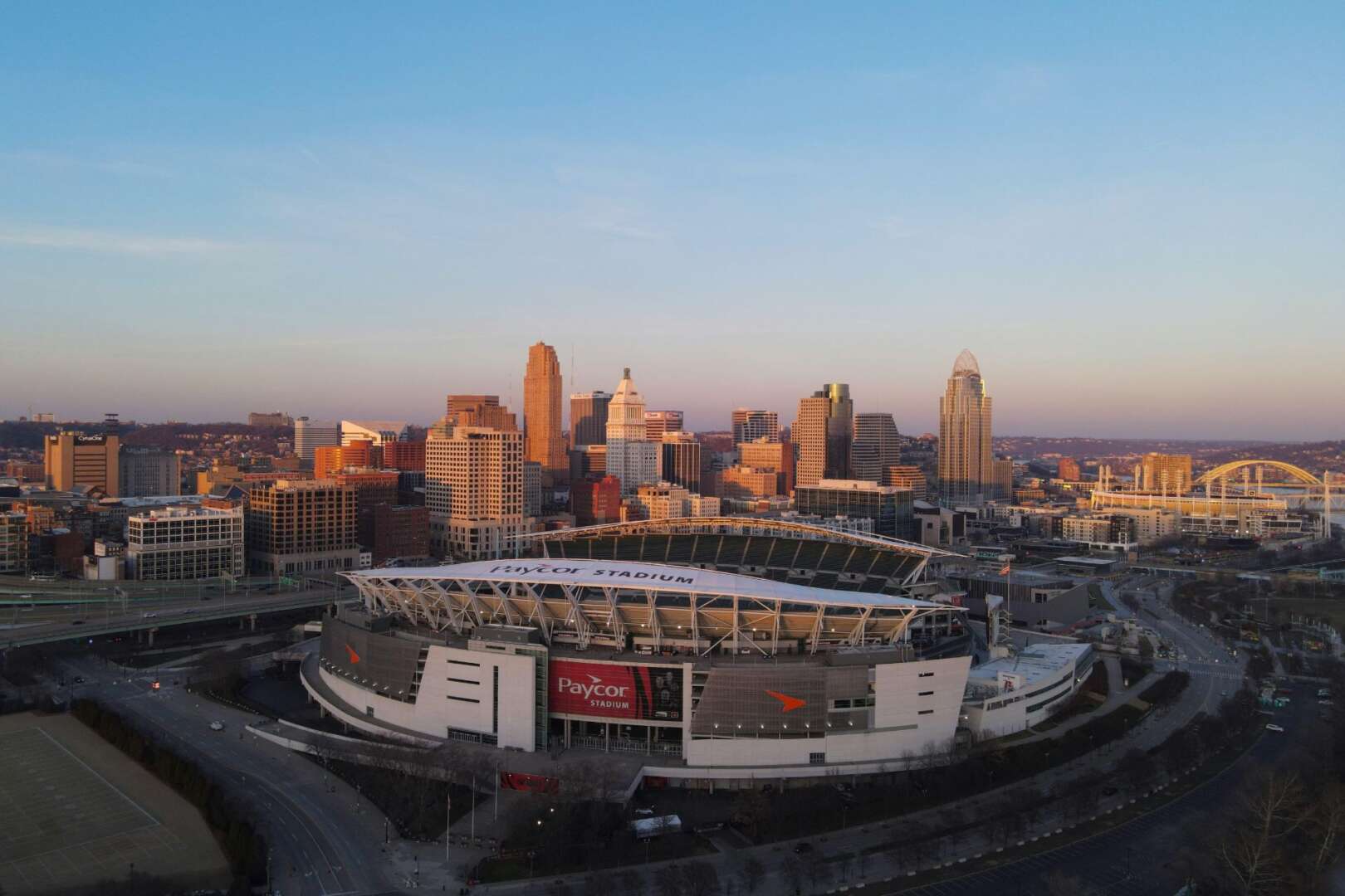 Aerial view of The Banks mixed-use development and Great American Ball Park along the Cincinnati riverfront at sunset.