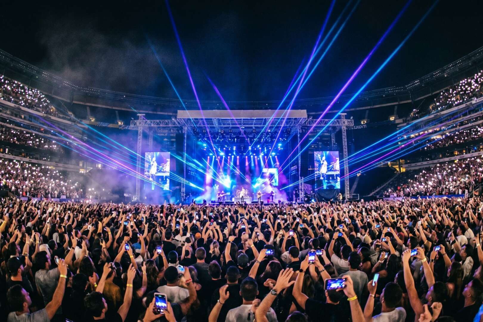 A massive crowd attending a lively stadium concert at night with bright blue stage lights, representing the booming 2026 entertainment and tourism growth in Cincinnati.