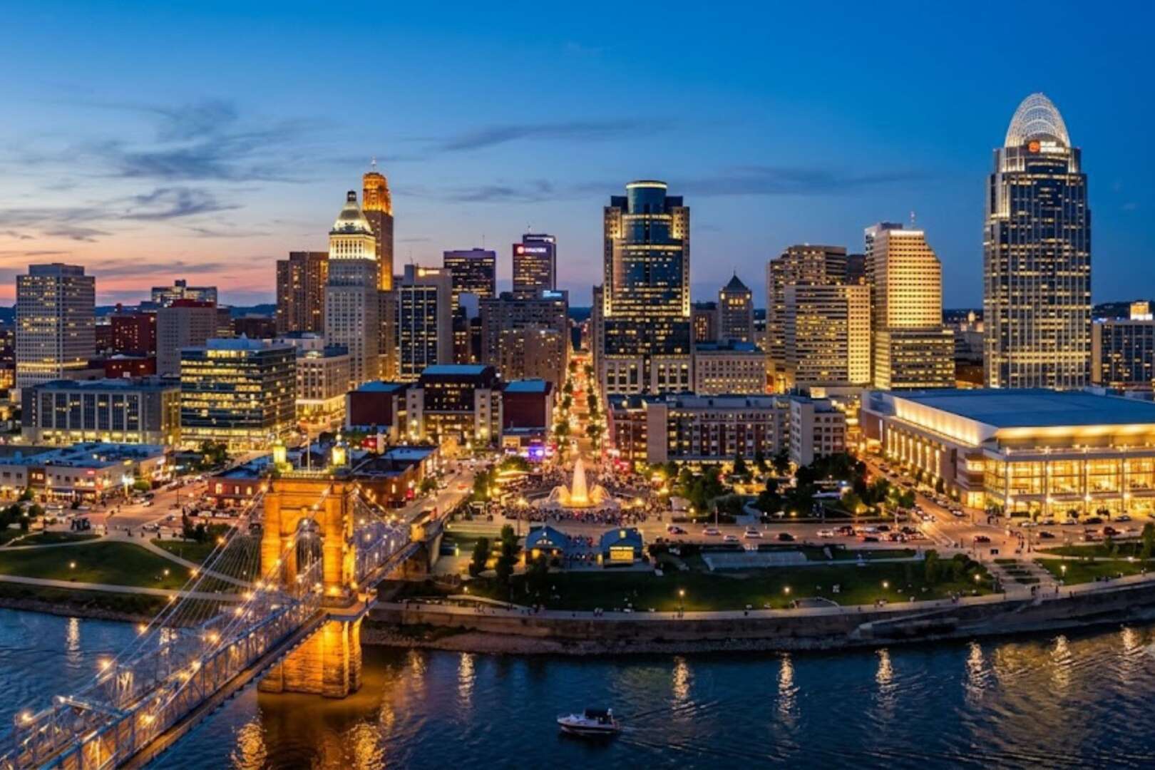 Nighttime skyline of downtown Cincinnati, Ohio, featuring the illuminated John A. Roebling Suspension Bridge crossing the Ohio River.