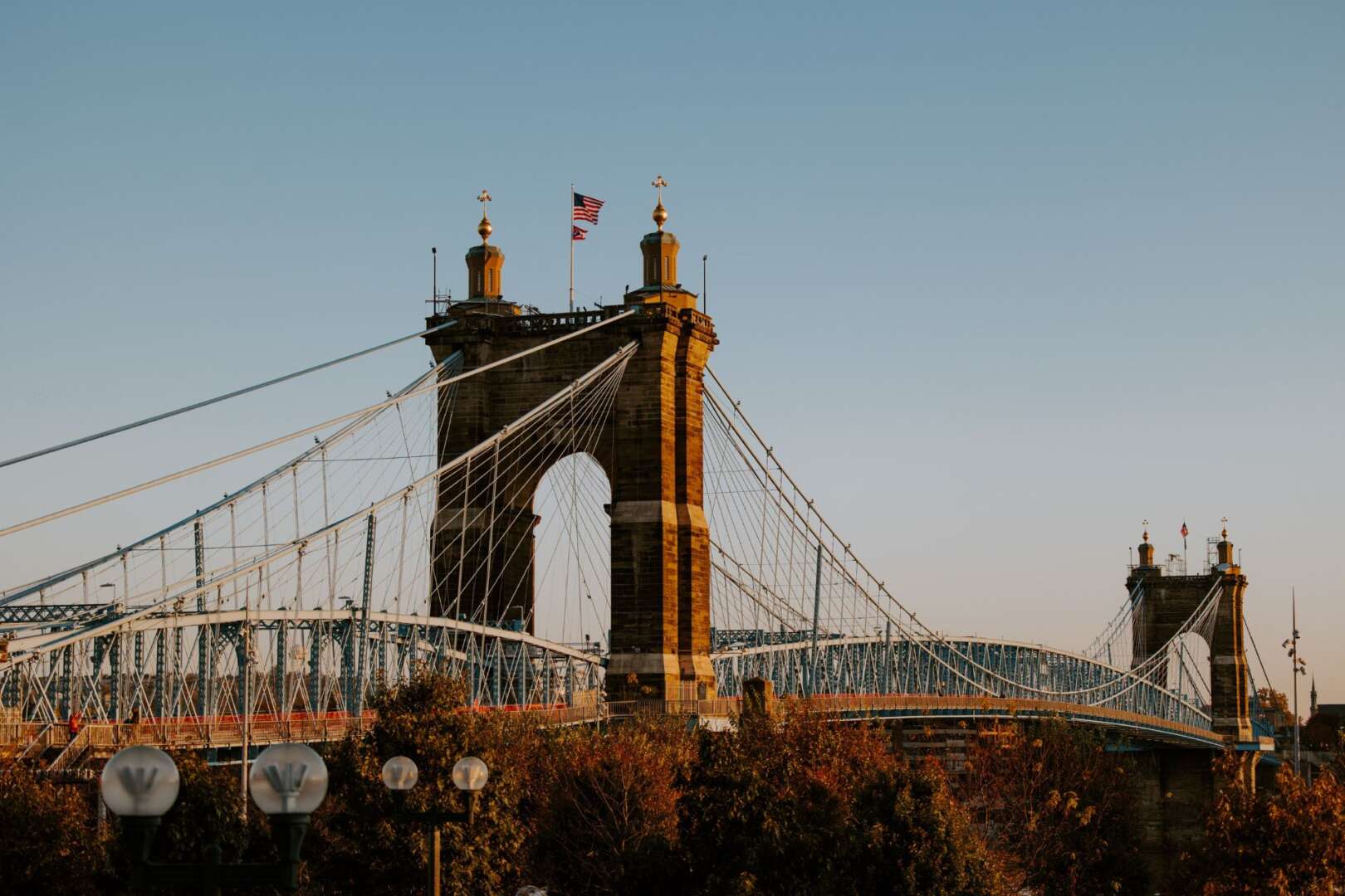The John A. Roebling Suspension Bridge in Cincinnati spanning the river at sunset.