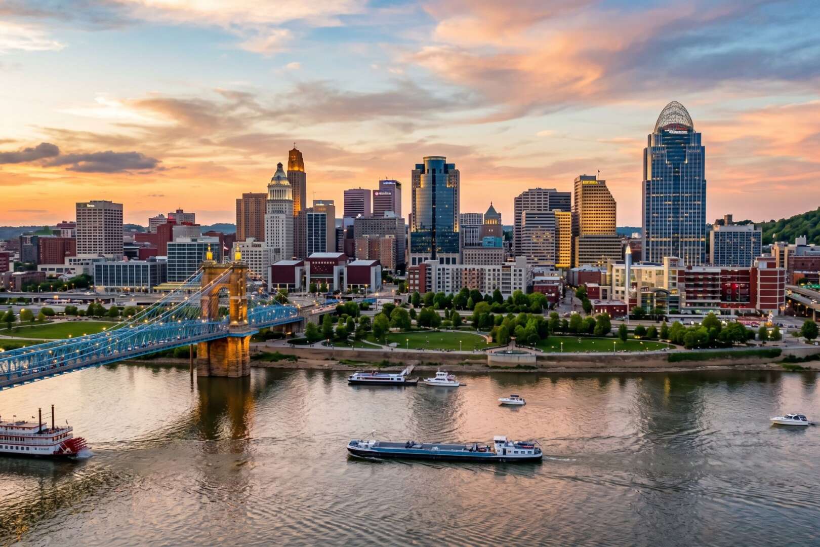 A panoramic view of the Cincinnati skyline and the Ohio River at sunset.